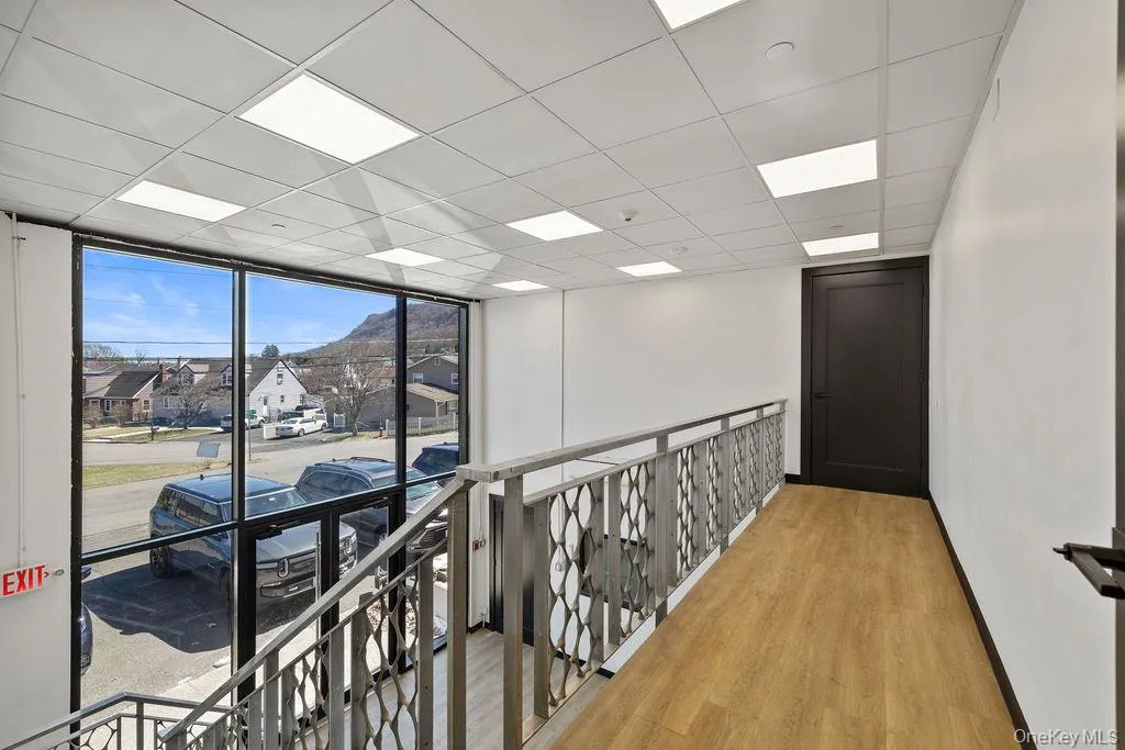 Corridor featuring a paneled ceiling, light wood-style floors, floor to ceiling windows, a residential view, and an upstairs landing Corridor featuring a paneled ceiling, light wood-style floors, floor to ceiling windows, a residential view, and an upstairs landing