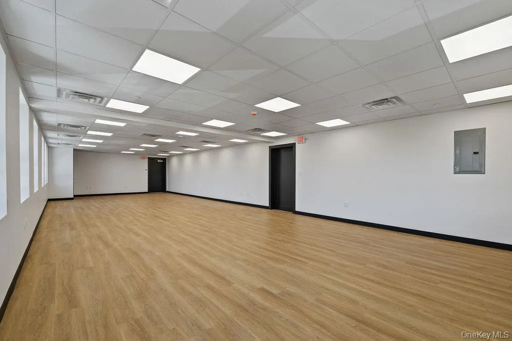 Empty room with electric panel, light wood-style floors, and a paneled ceiling Empty room with electric panel, light wood-style floors, and a paneled ceiling