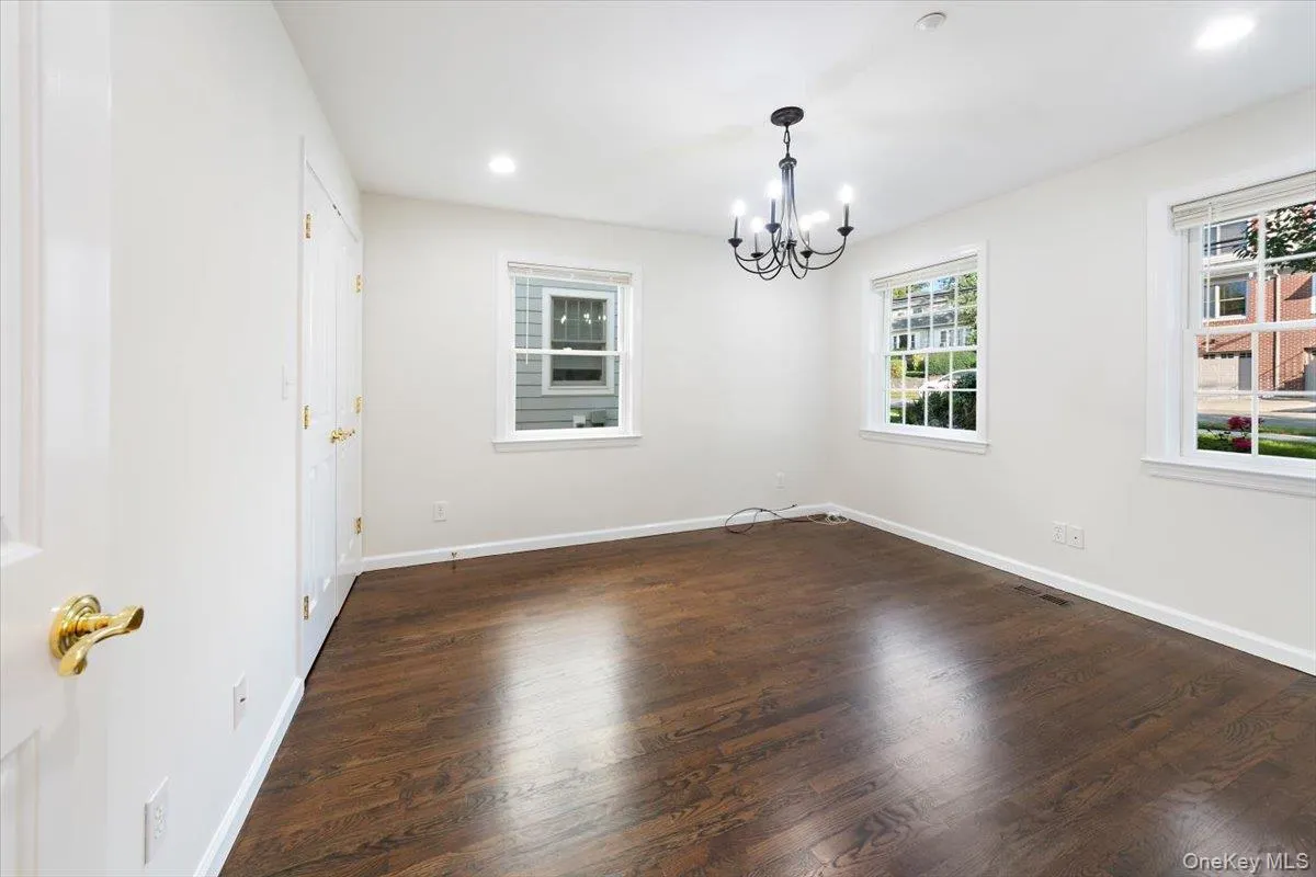 Unfurnished room with dark wood finished floors, a chandelier, and recessed lighting Unfurnished room with dark wood finished floors, a chandelier, and recessed lighting
