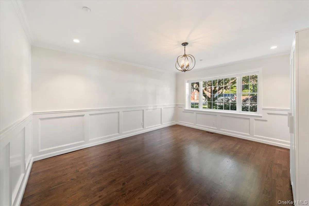 Unfurnished dining area with recessed lighting, wainscoting, a chandelier, a decorative wall, and dark wood-style flooring Unfurnished dining area with recessed lighting, wainscoting, a chandelier, a decorative wall, and dark wood-style flooring