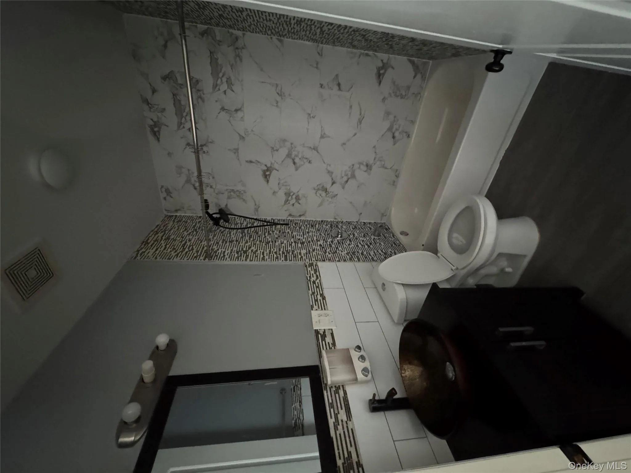 Full bathroom with shower / washtub combination, vanity, dark wood-type flooring, tile walls, and tasteful backsplash Full bathroom with shower / washtub combination, vanity, dark wood-type flooring, tile walls, and tasteful backsplash