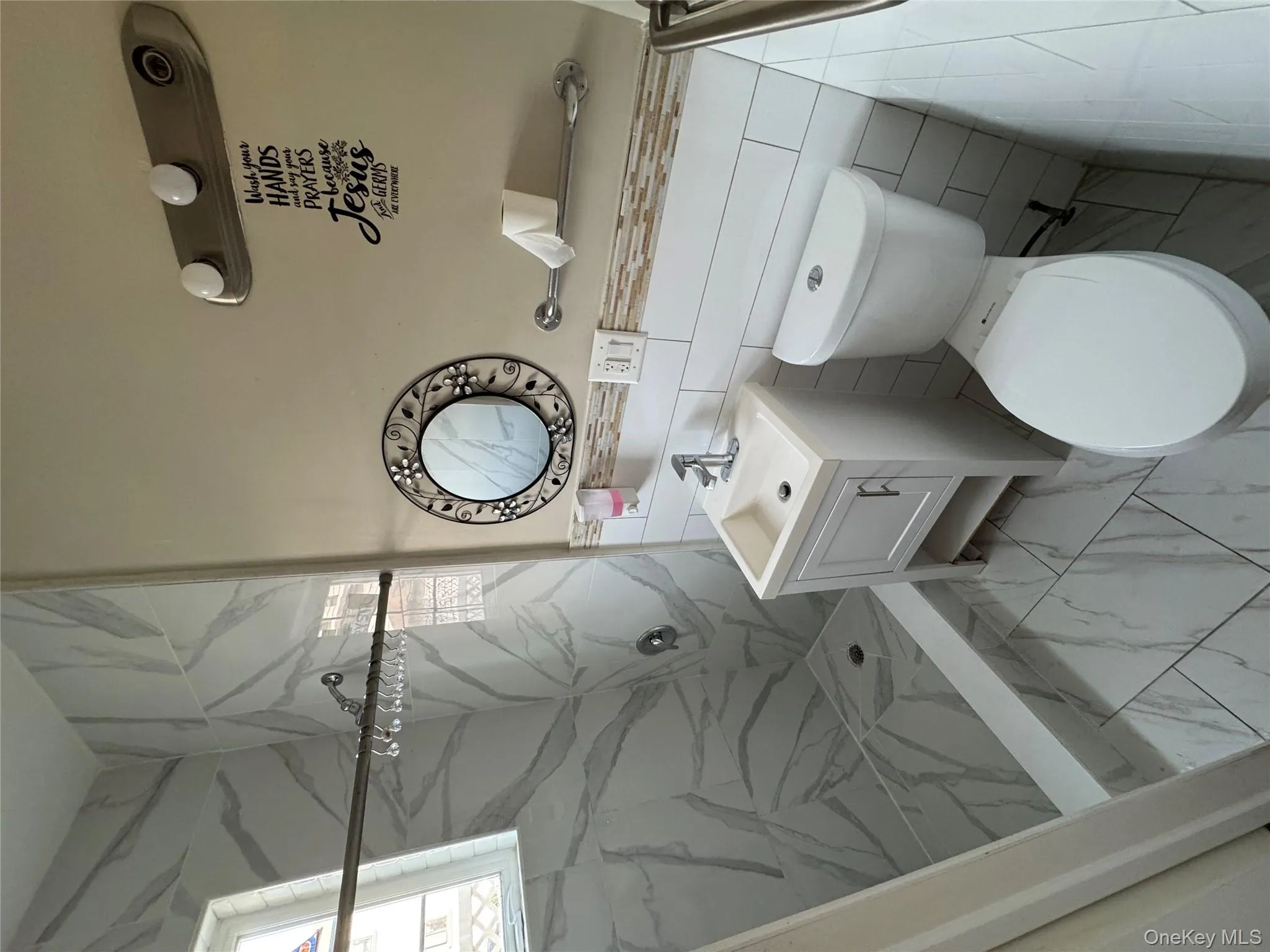 Bathroom with vanity, a marble finish shower, tile walls, and light marble finish floors Bathroom with vanity, a marble finish shower, tile walls, and light marble finish floors
