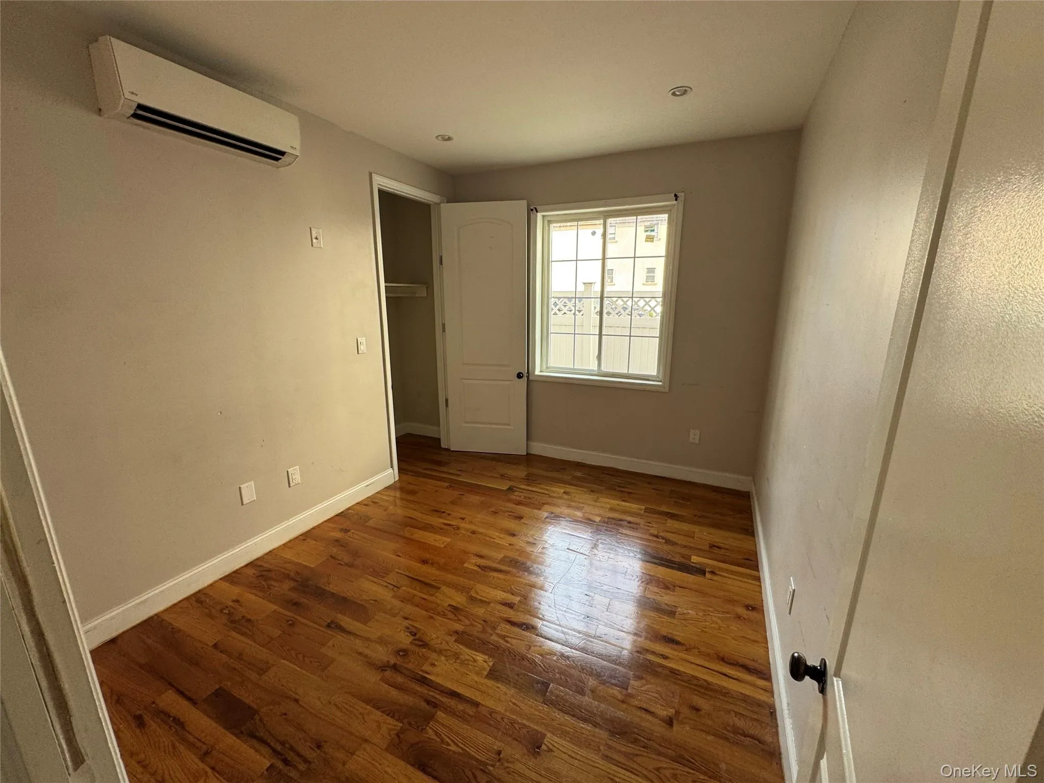 Unfurnished bedroom with wood finished floors and a wall unit AC Unfurnished bedroom with wood finished floors and a wall unit AC