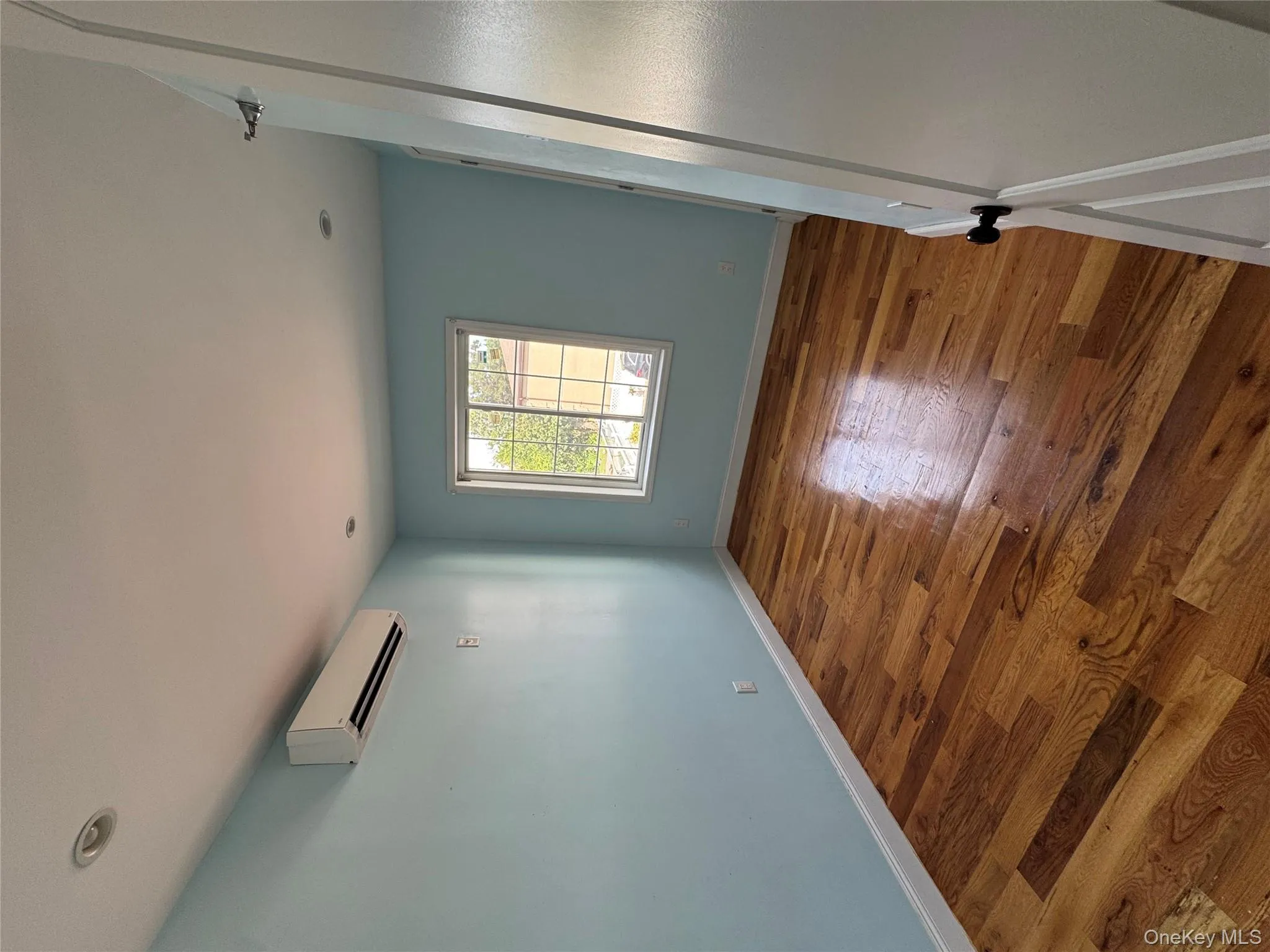 Unfurnished room with wood-type flooring, a wall mounted air conditioner, and recessed lighting Unfurnished room with wood-type flooring, a wall mounted air conditioner, and recessed lighting
