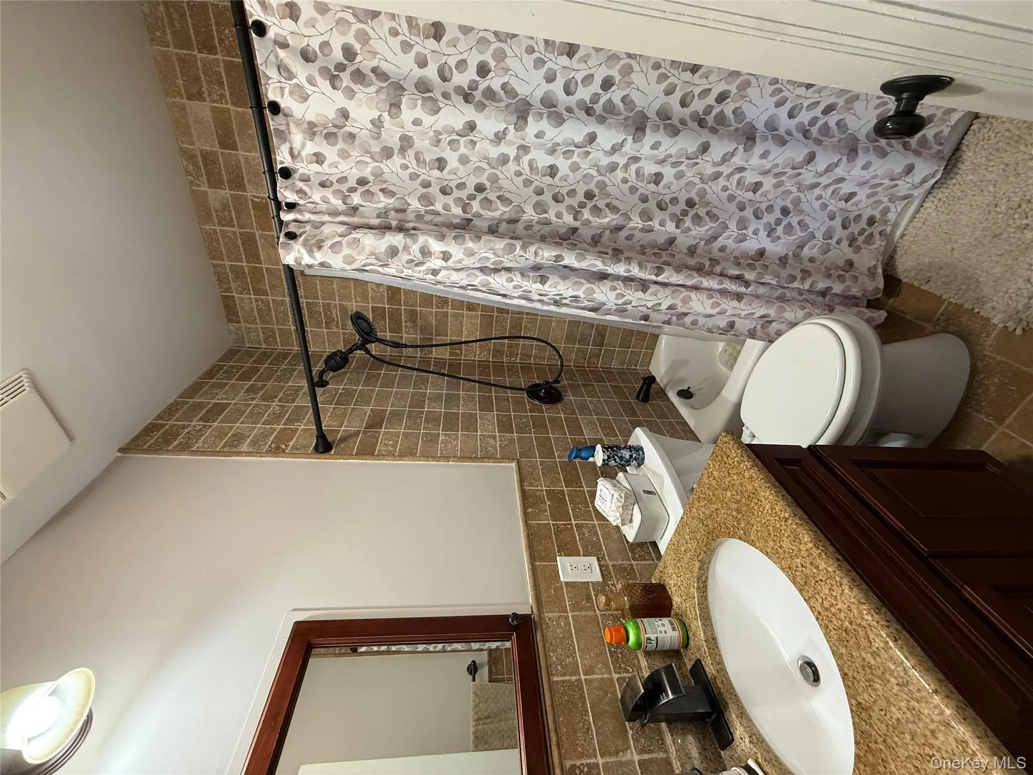 Bathroom featuring vanity, shower / bath combo, decorative backsplash, and tile walls Bathroom featuring vanity, shower / bath combo, decorative backsplash, and tile walls