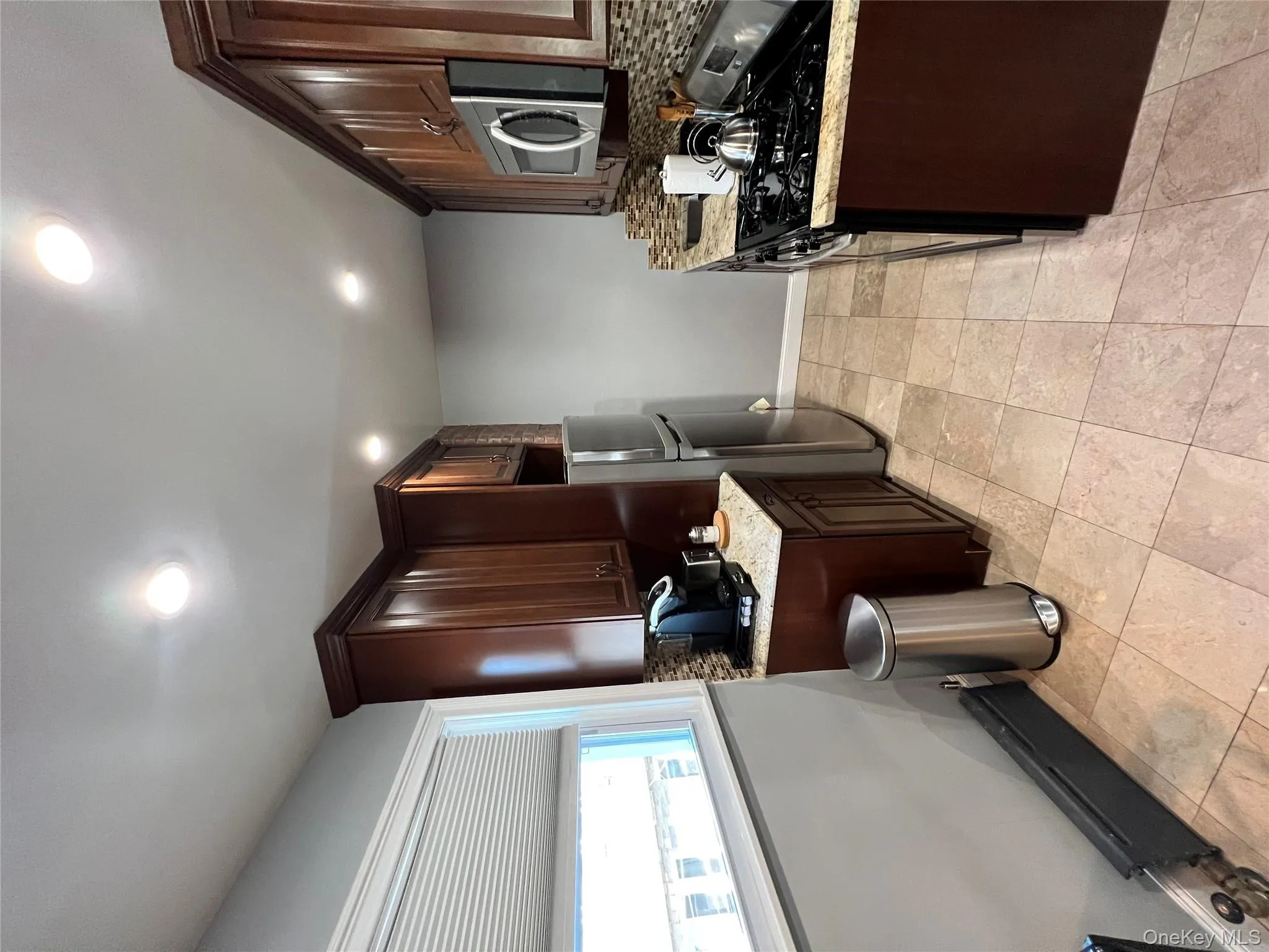 Kitchen featuring backsplash, stove, dark brown cabinets, a baseboard radiator, and refrigerator Kitchen featuring backsplash, stove, dark brown cabinets, a baseboard radiator, and refrigerator