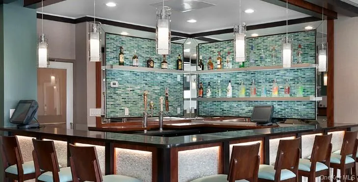 Indoor wet bar with open shelves, backsplash, dark countertops, decorative light fixtures, and recessed lighting Indoor wet bar with open shelves, backsplash, dark countertops, decorative light fixtures, and recessed lighting