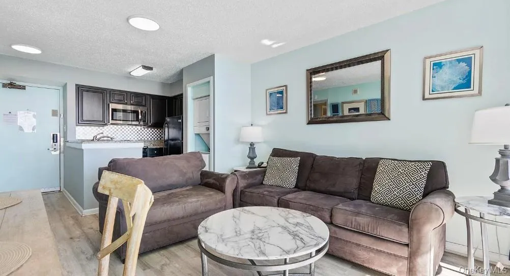 Living room featuring light wood-style flooring and a textured ceiling Living room featuring light wood-style flooring and a textured ceiling