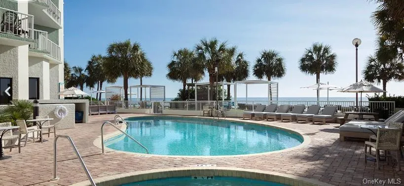 Community pool with a patio and a water view Community pool with a patio and a water view