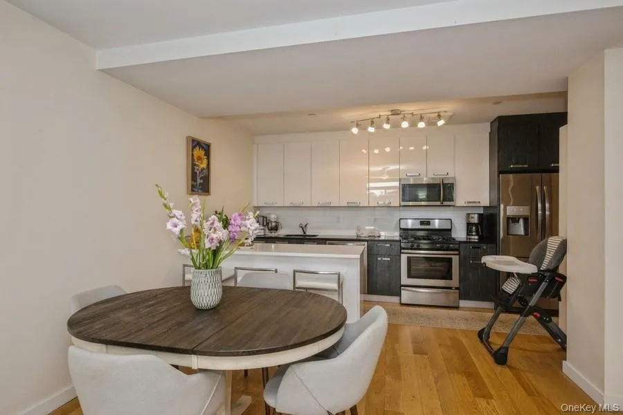 Kitchen with tasteful backsplash, appliances with stainless steel finishes, light wood finished floors, and white cabinetry Kitchen with tasteful backsplash, appliances with stainless steel finishes, light wood finished floors, and white cabinetry