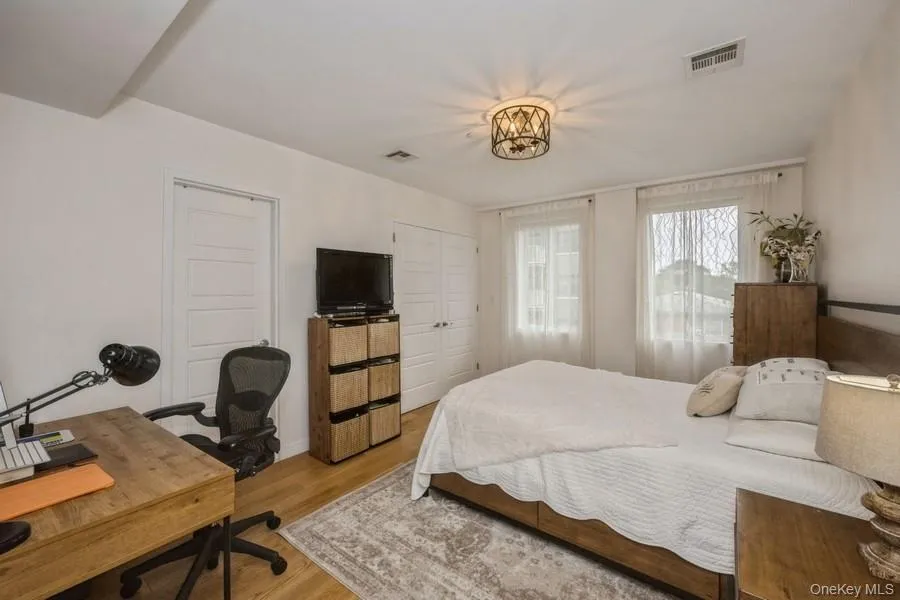 Bedroom featuring a desk, wood finished floors, and two closets Bedroom featuring a desk, wood finished floors, and two closets