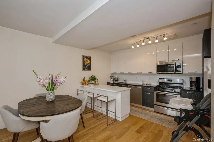 Kitchen featuring appliances with stainless steel finishes, decorative backsplash, white cabinets, and a kitchen breakfast bar Kitchen featuring appliances with stainless steel finishes, decorative backsplash, white cabinets, and a kitchen breakfast bar