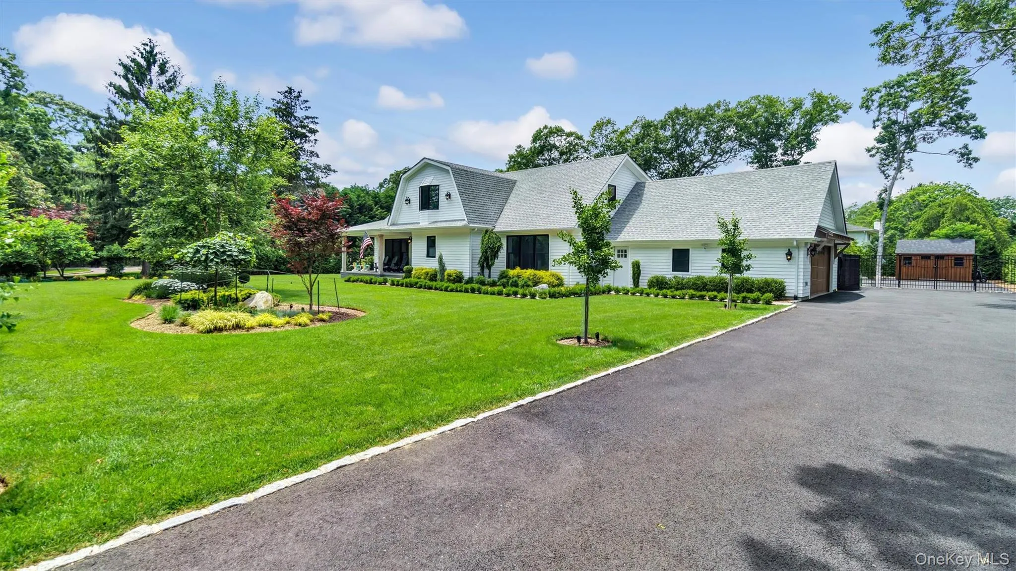 View of front of home featuring a front lawn, covered porch, a shingled roof, driveway, and a gambrel roof View of front of home featuring a front lawn, covered porch, a shingled roof, driveway, and a gambrel roof