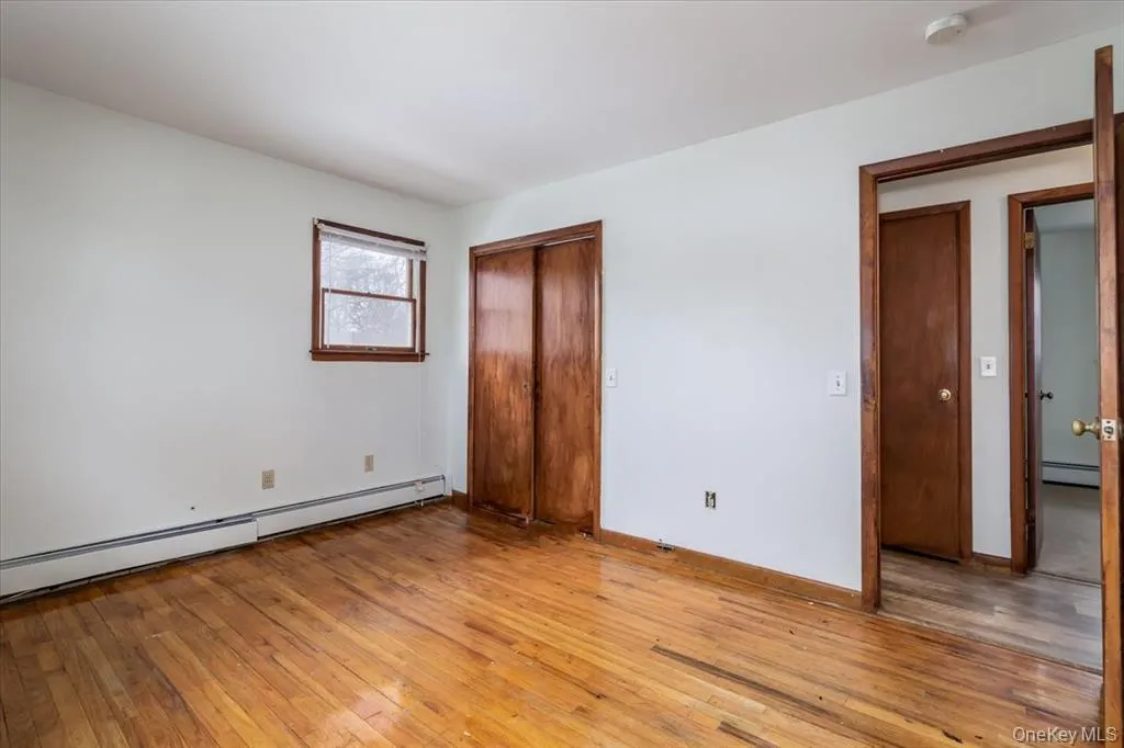 Unfurnished bedroom with light wood finished floors, a baseboard heating unit, a closet, and a baseboard radiator Unfurnished bedroom with light wood finished floors, a baseboard heating unit, a closet, and a baseboard radiator