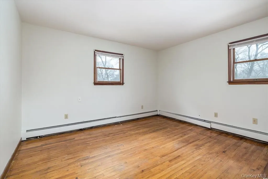 Unfurnished room featuring light wood-type flooring, a baseboard radiator, and a baseboard heating unit Unfurnished room featuring light wood-type flooring, a baseboard radiator, and a baseboard heating unit