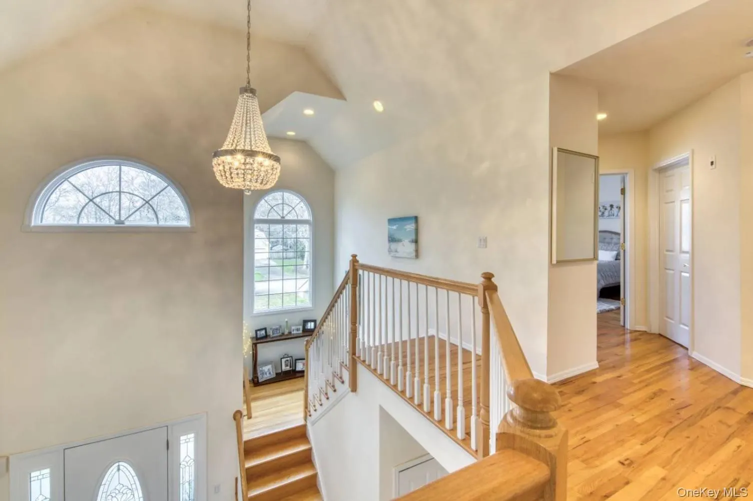 Foyer with high vaulted ceiling, light wood-style flooring, a chandelier, and recessed lighting Foyer with high vaulted ceiling, light wood-style flooring, a chandelier, and recessed lighting