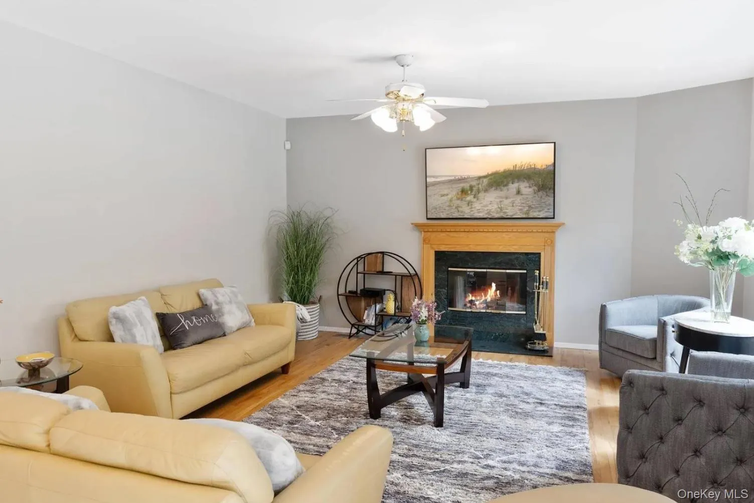 Living room with a high end fireplace, wood finished floors, and a ceiling fan Living room with a high end fireplace, wood finished floors, and a ceiling fan