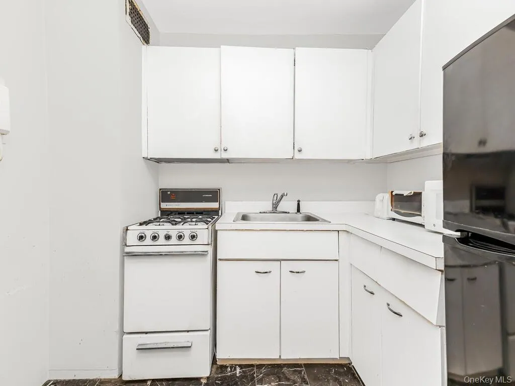 Kitchen featuring white cabinets, white appliances, and light countertops Kitchen featuring white cabinets, white appliances, and light countertops