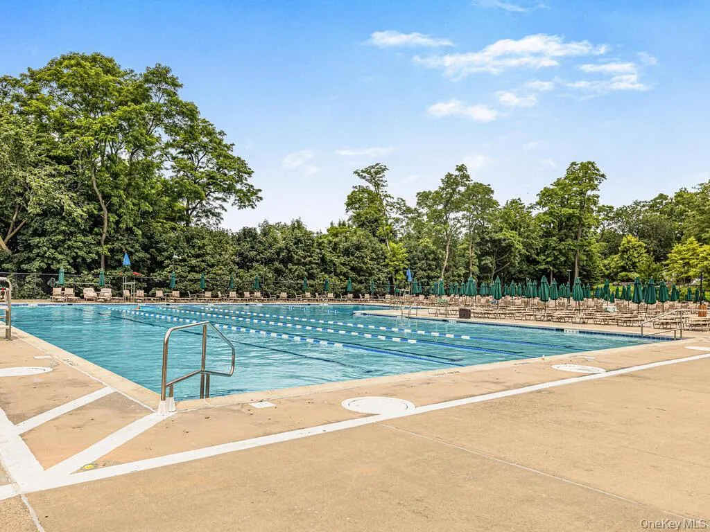 Community pool with a patio and view of wooded area Community pool with a patio and view of wooded area