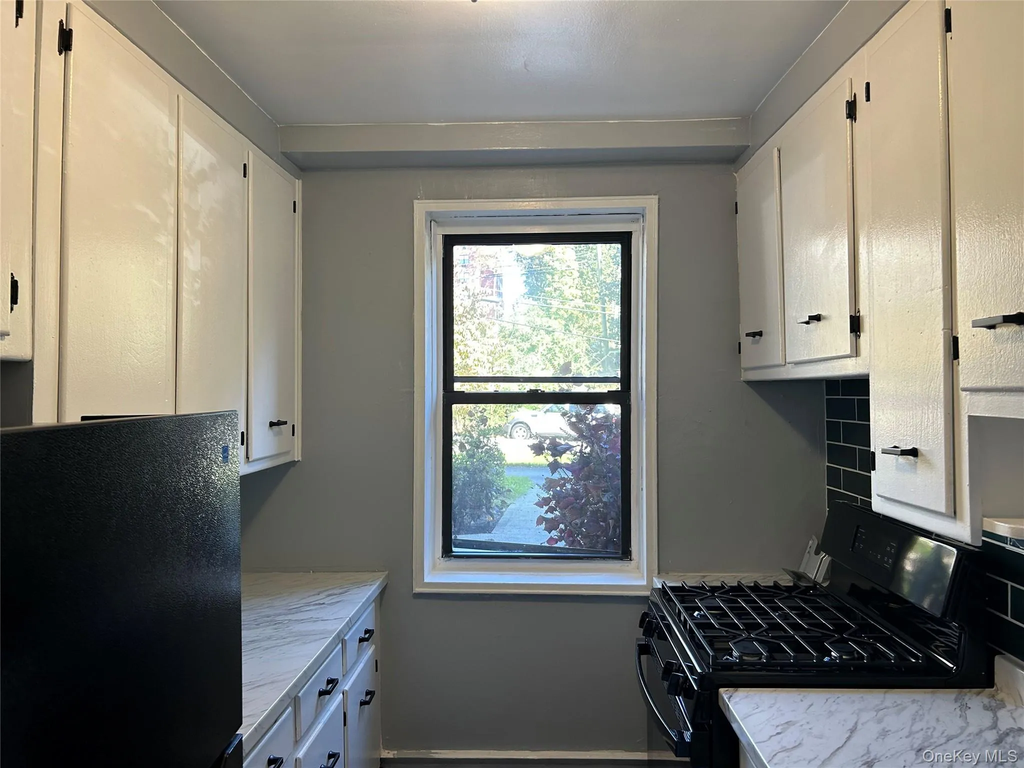 Kitchen featuring black appliances, light countertops, and white cabinets Kitchen featuring black appliances, light countertops, and white cabinets