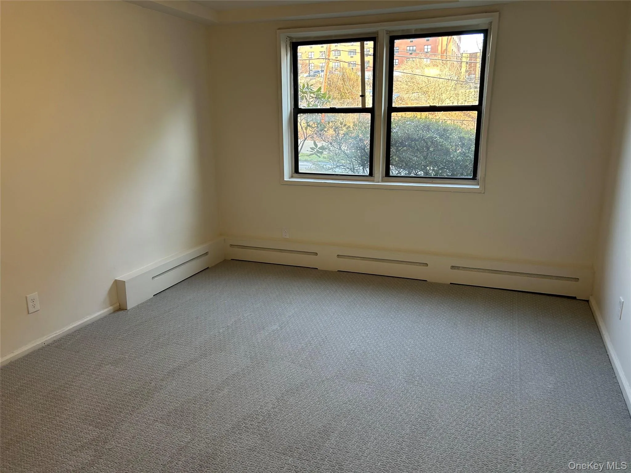 Empty room featuring carpet floors and baseboard heating Empty room featuring carpet floors and baseboard heating