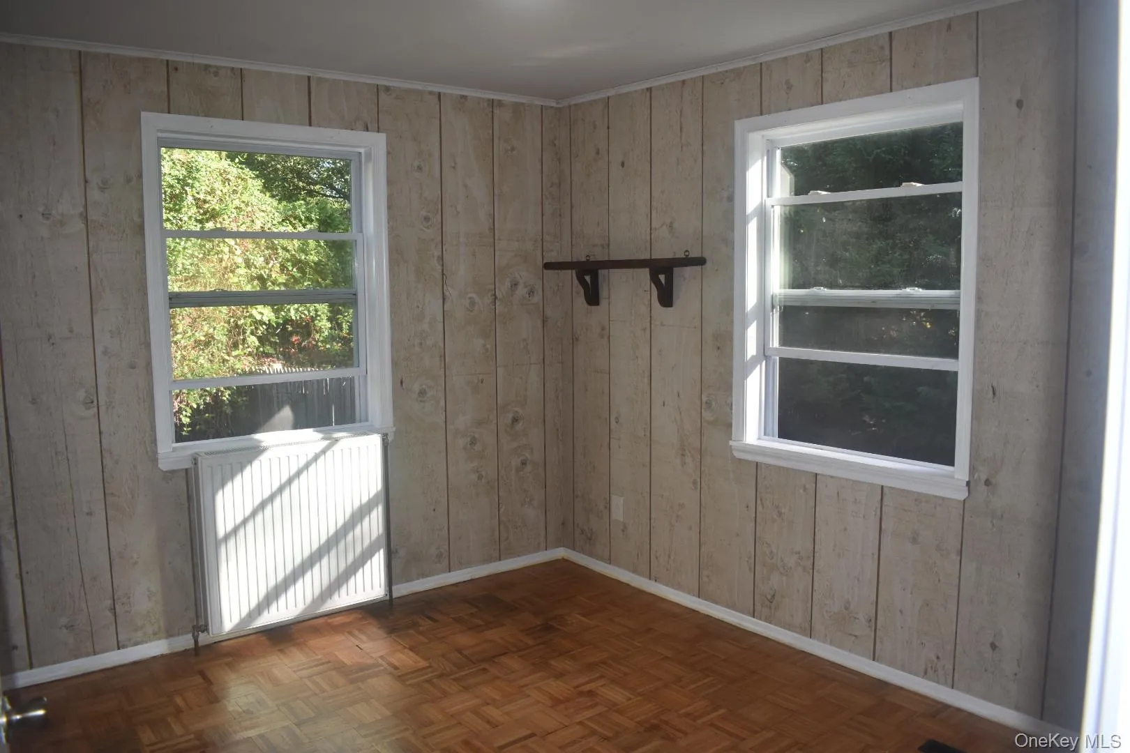 Doorway featuring radiator, wooden walls, and ornamental molding Doorway featuring radiator, wooden walls, and ornamental molding