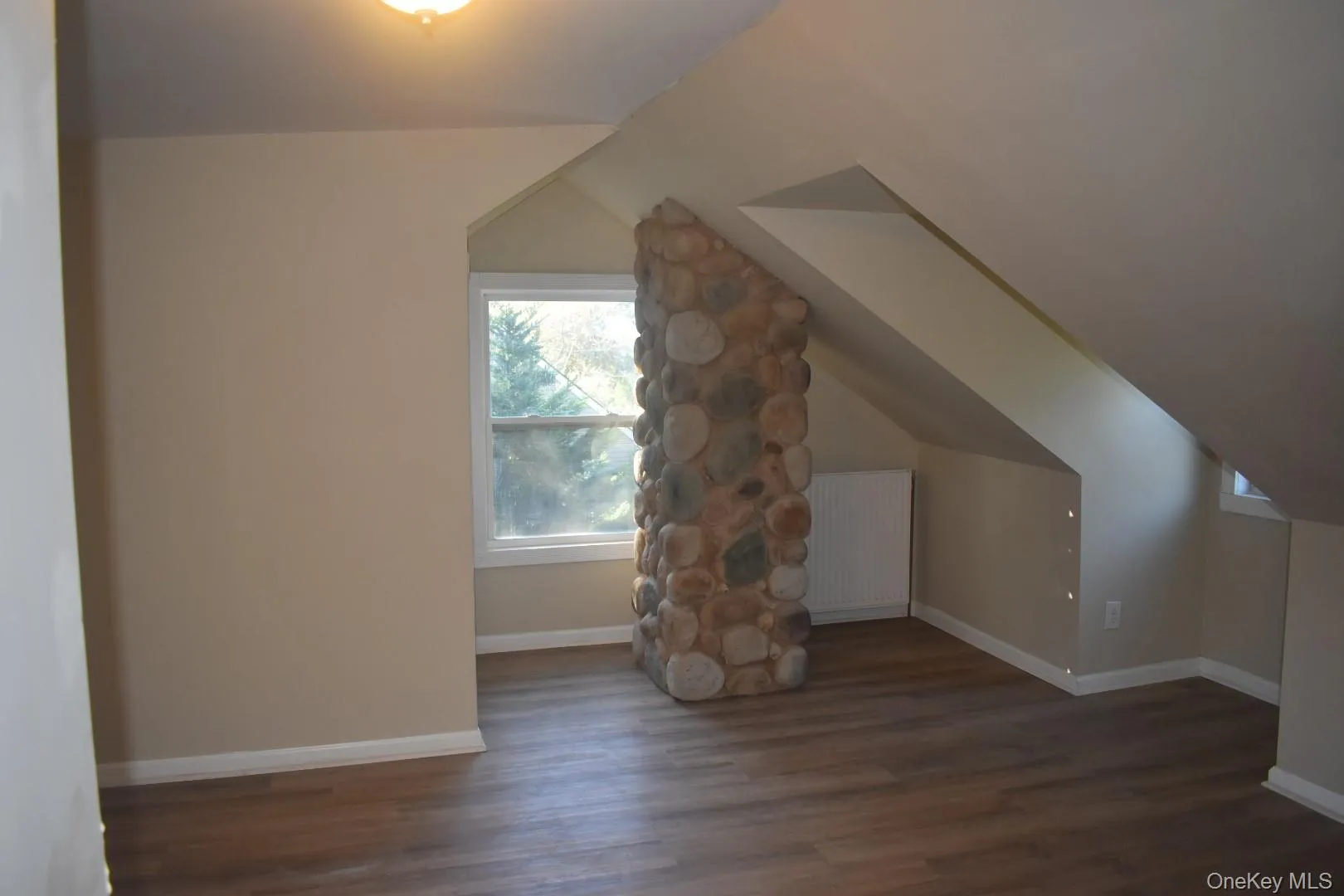 Bonus room with dark wood-style floors, vaulted ceiling, and radiator heating unit Bonus room with dark wood-style floors, vaulted ceiling, and radiator heating unit
