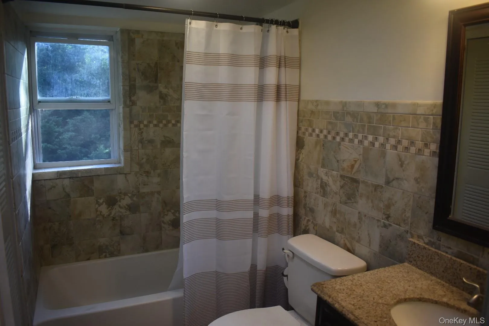 Full bathroom featuring tile walls, shower / bathtub combination with curtain, and vanity Full bathroom featuring tile walls, shower / bathtub combination with curtain, and vanity