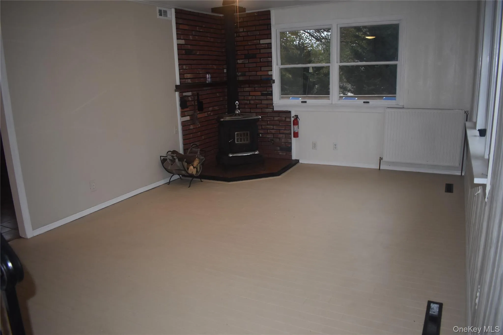 Unfurnished living room with a wood stove and radiator heating unit Unfurnished living room with a wood stove and radiator heating unit