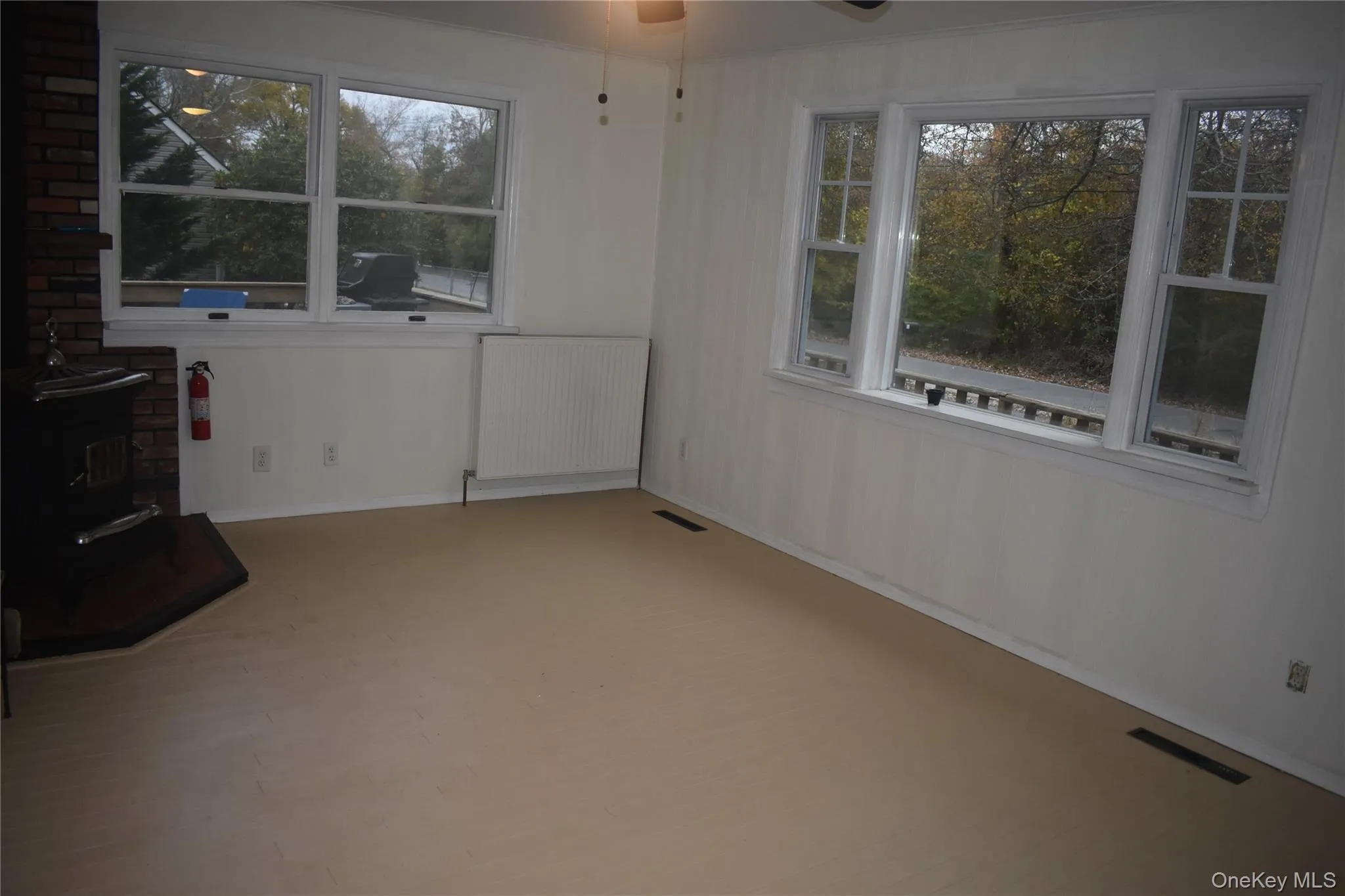 Unfurnished sunroom featuring a wood stove and radiator heating unit Unfurnished sunroom featuring a wood stove and radiator heating unit
