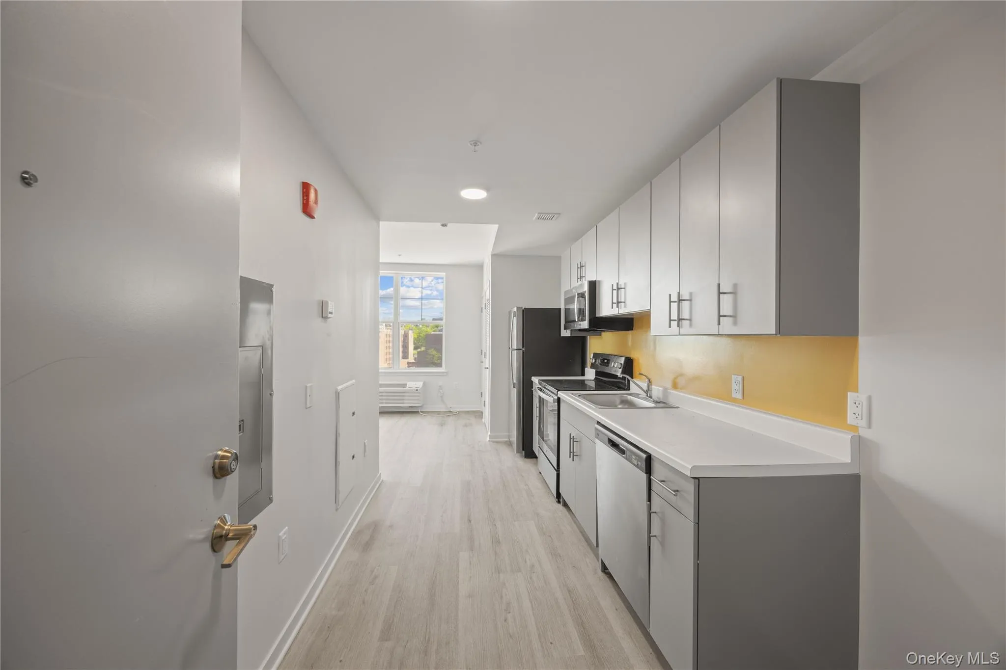 Kitchen featuring light countertops, light wood-style floors, stainless steel appliances, gray cabinets, and white cabinets Kitchen featuring light countertops, light wood-style floors, stainless steel appliances, gray cabinets, and white cabinets