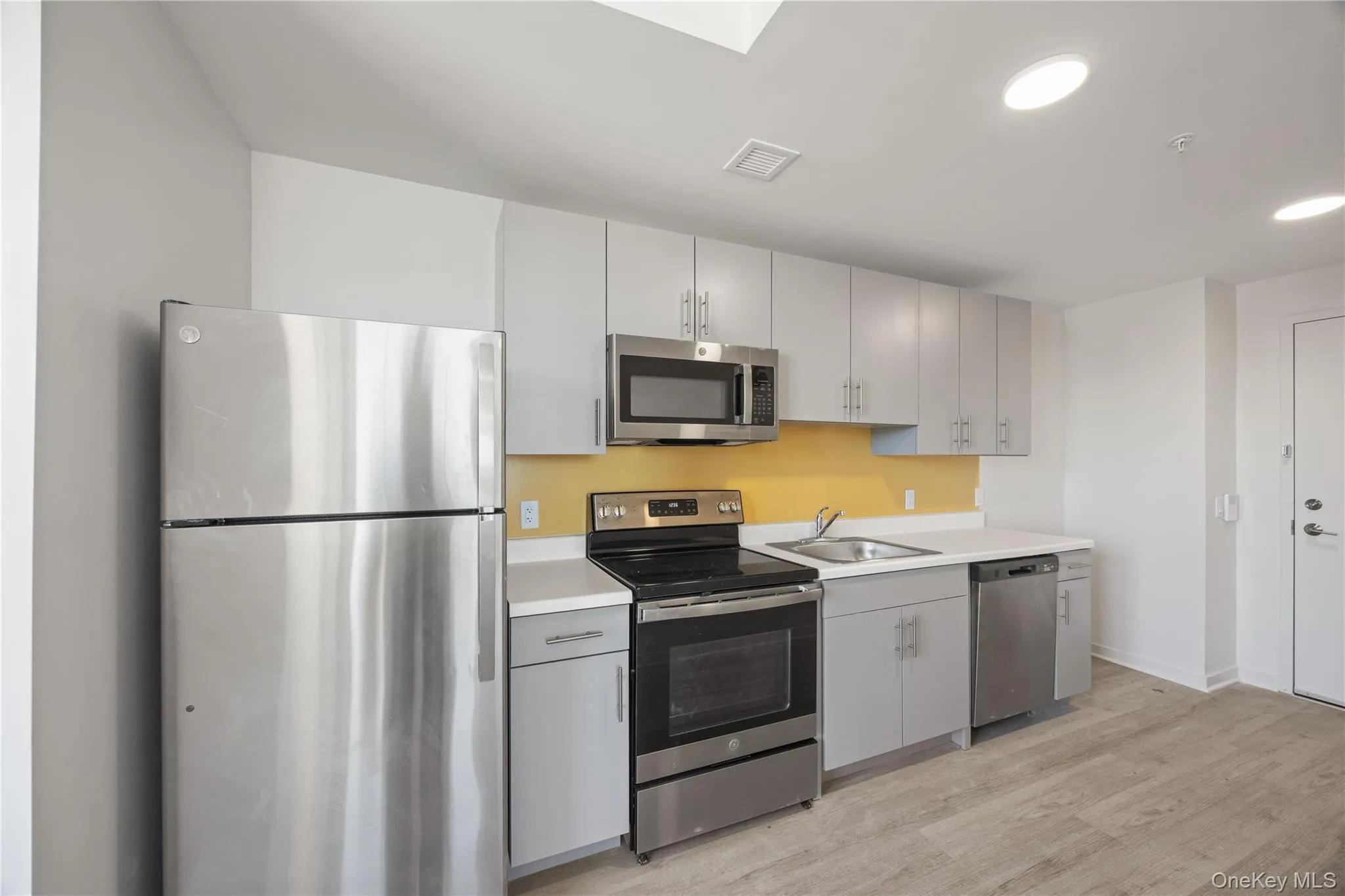 Kitchen featuring appliances with stainless steel finishes, light countertops, light wood-style floors, recessed lighting, and a skylight Kitchen featuring appliances with stainless steel finishes, light countertops, light wood-style floors, recessed lighting, and a skylight