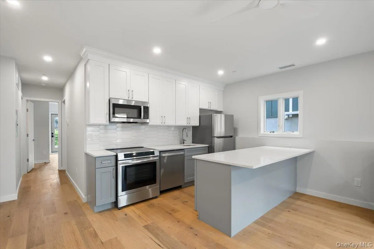 Kitchen with stainless steel appliances, light countertops, light wood-style floors, backsplash, and recessed lighting Kitchen with stainless steel appliances, light countertops, light wood-style floors, backsplash, and recessed lighting