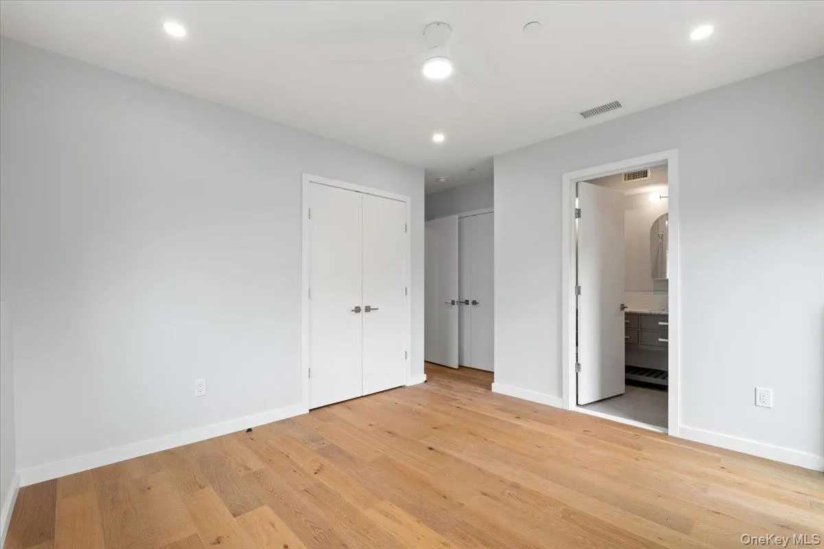 Unfurnished bedroom featuring light wood-type flooring, ensuite bathroom, multiple closets, recessed lighting, and ceiling fan Unfurnished bedroom featuring light wood-type flooring, ensuite bathroom, multiple closets, recessed lighting, and ceiling fan