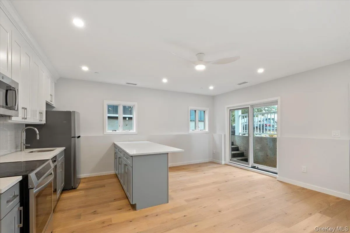 Kitchen with appliances with stainless steel finishes, gray cabinetry, ceiling fan, light countertops, and light wood-style floors Kitchen with appliances with stainless steel finishes, gray cabinetry, ceiling fan, light countertops, and light wood-style floors
