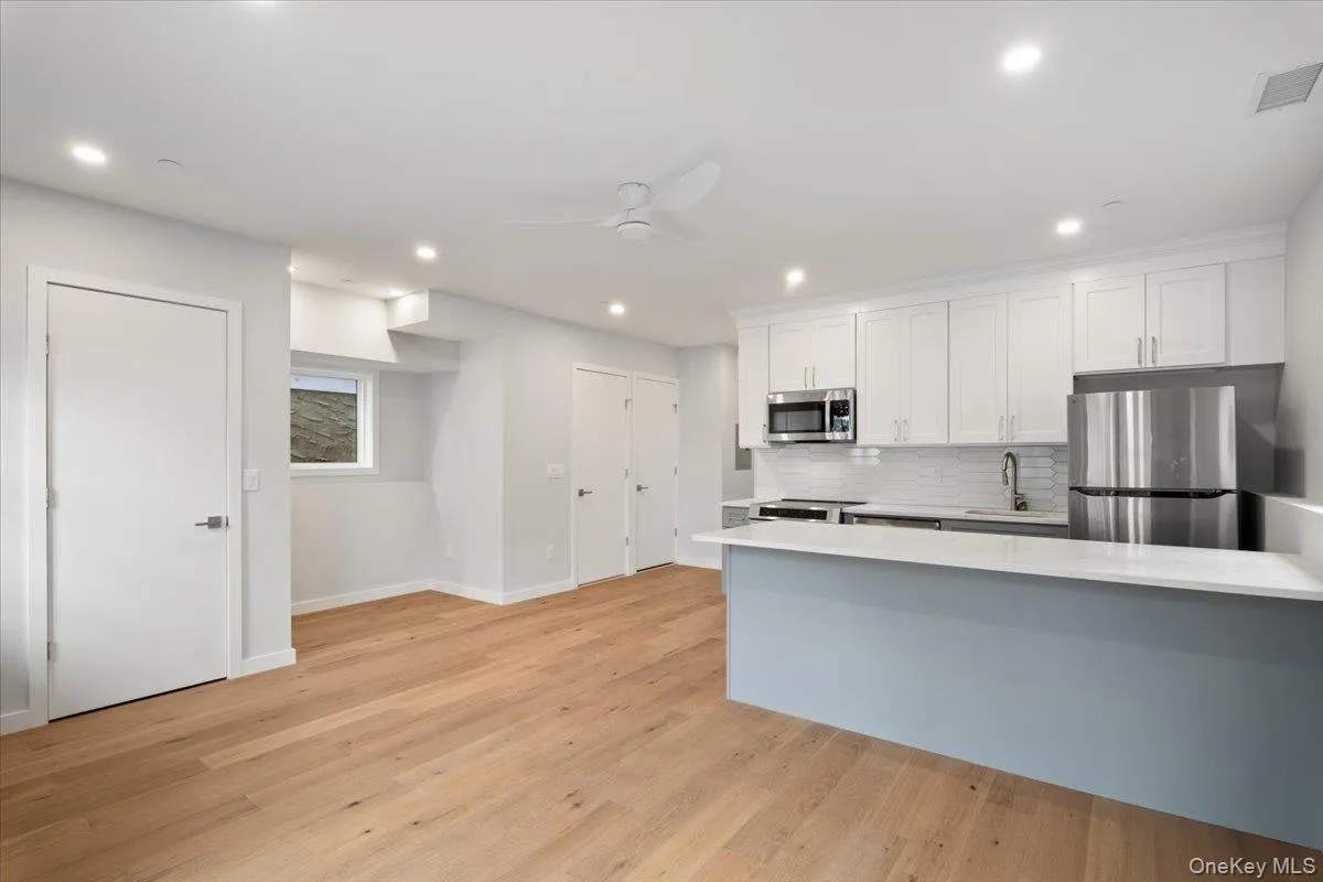 Kitchen featuring stainless steel appliances, ceiling fan, white cabinets, light countertops, and tasteful backsplash Kitchen featuring stainless steel appliances, ceiling fan, white cabinets, light countertops, and tasteful backsplash