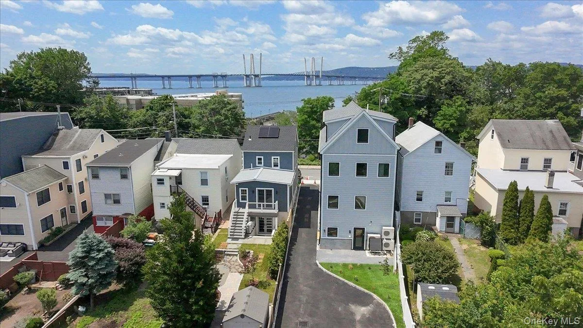 Aerial view of residential area featuring a notable bridge and a nearby body of water Aerial view of residential area featuring a notable bridge and a nearby body of water