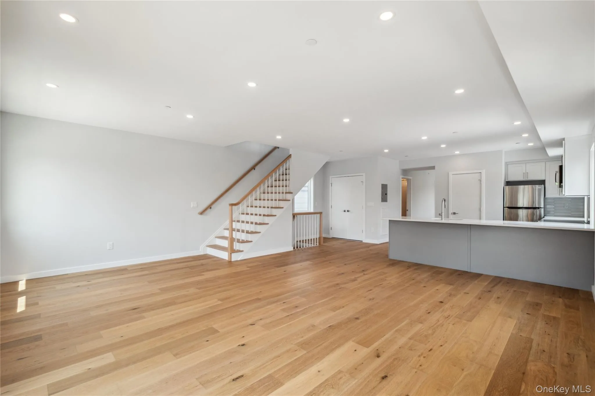 Unfurnished living room with light wood-type flooring, stairs, and recessed lighting Unfurnished living room with light wood-type flooring, stairs, and recessed lighting