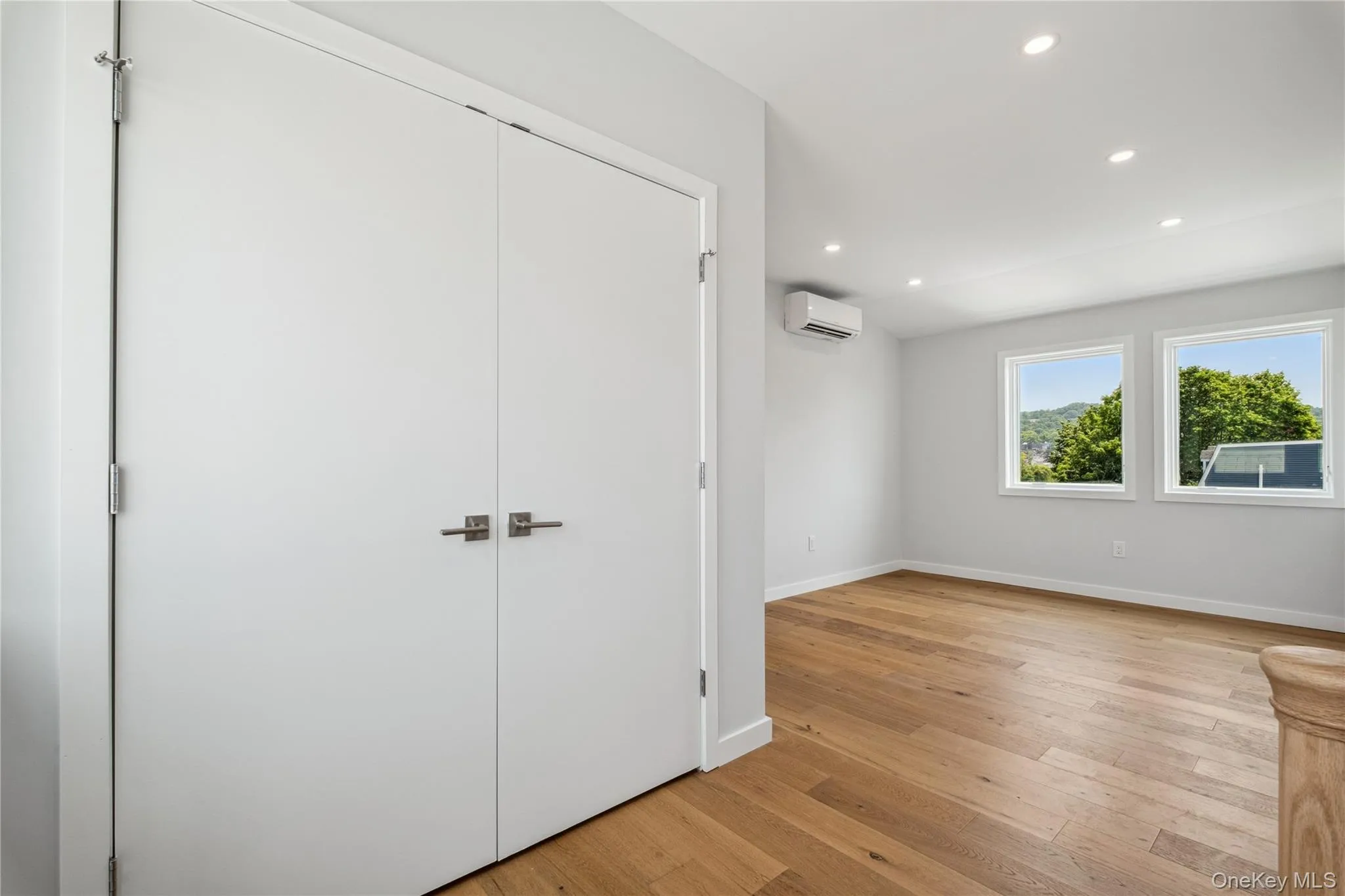 Unfurnished bedroom with a wall mounted air conditioner, recessed lighting, light wood finished floors, and a closet Unfurnished bedroom with a wall mounted air conditioner, recessed lighting, light wood finished floors, and a closet
