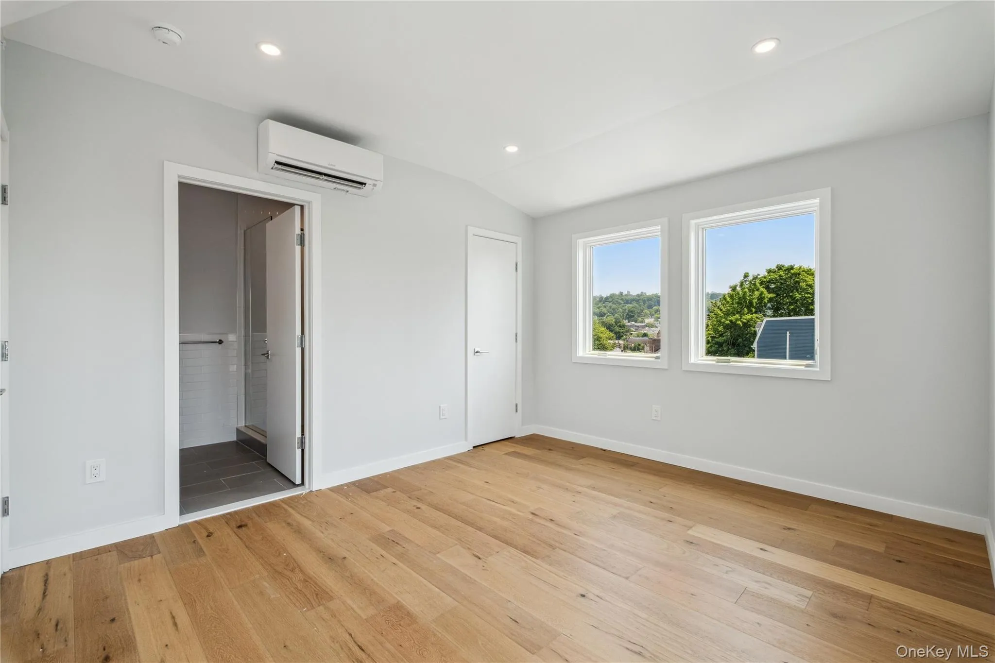Unfurnished bedroom featuring a wall mounted air conditioner, light wood-style flooring, recessed lighting, vaulted ceiling, and ensuite bathroom Unfurnished bedroom featuring a wall mounted air conditioner, light wood-style flooring, recessed lighting, vaulted ceiling, and ensuite bathroom