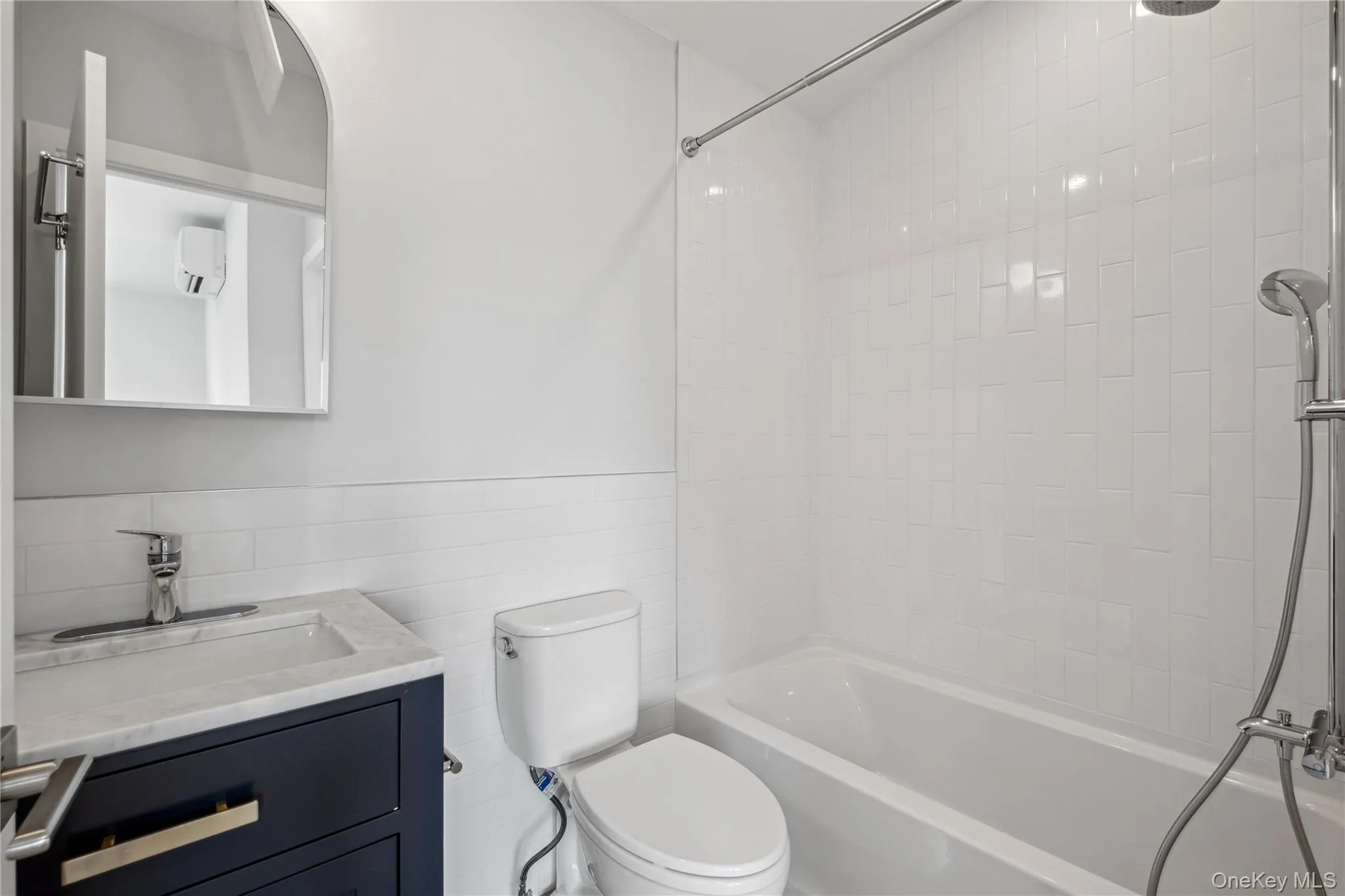 Bathroom with vanity, tub / shower combination, tile walls, and a wainscoted wall Bathroom with vanity, tub / shower combination, tile walls, and a wainscoted wall