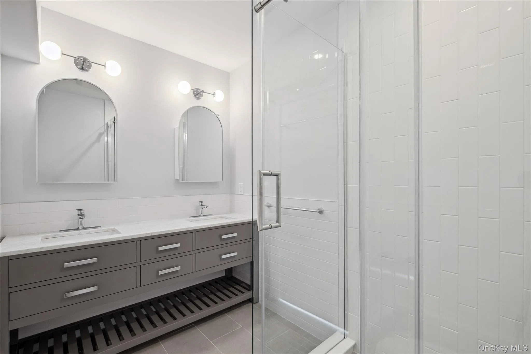 Full bathroom with a stall shower, double vanity, and tile patterned floors Full bathroom with a stall shower, double vanity, and tile patterned floors