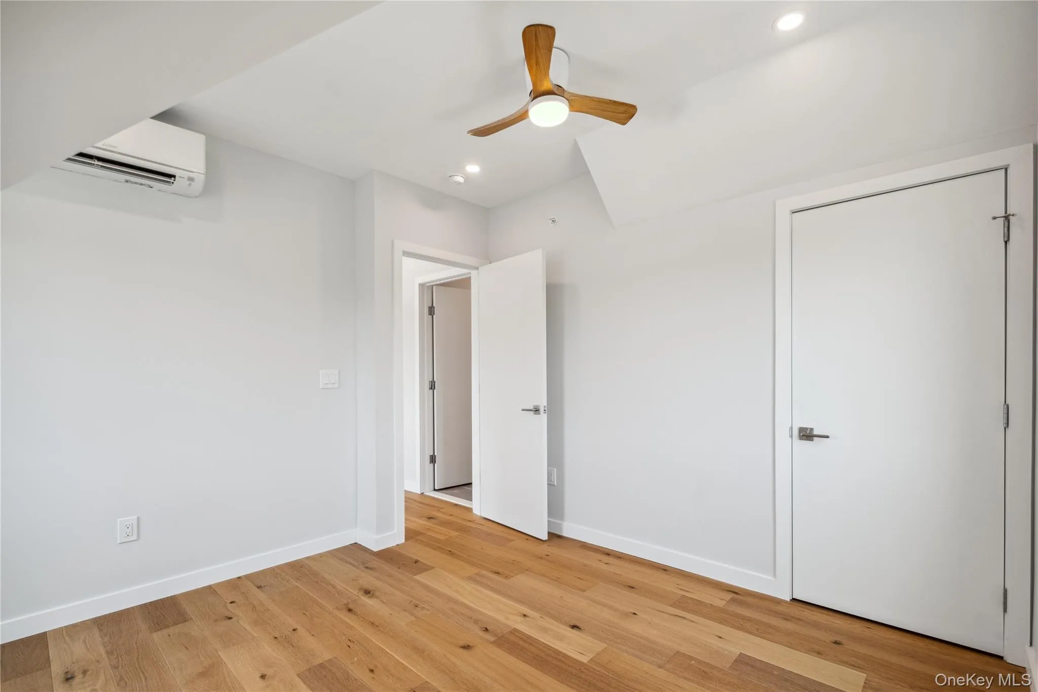 Unfurnished bedroom featuring a wall mounted AC, light wood-style flooring, recessed lighting, and a ceiling fan Unfurnished bedroom featuring a wall mounted AC, light wood-style flooring, recessed lighting, and a ceiling fan