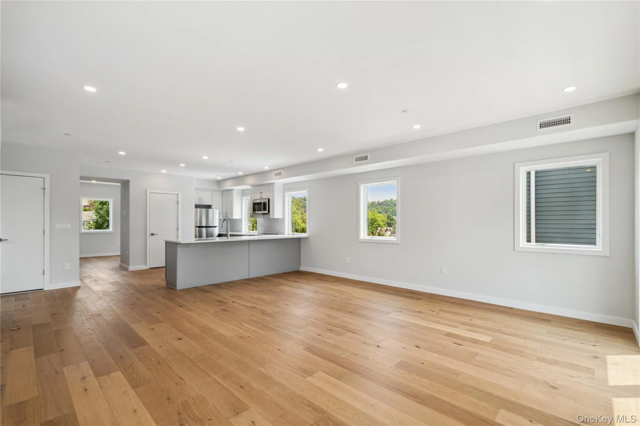 Kitchen with appliances with stainless steel finishes, a peninsula, open floor plan, light wood finished floors, and light countertops Kitchen with appliances with stainless steel finishes, a peninsula, open floor plan, light wood finished floors, and light countertops