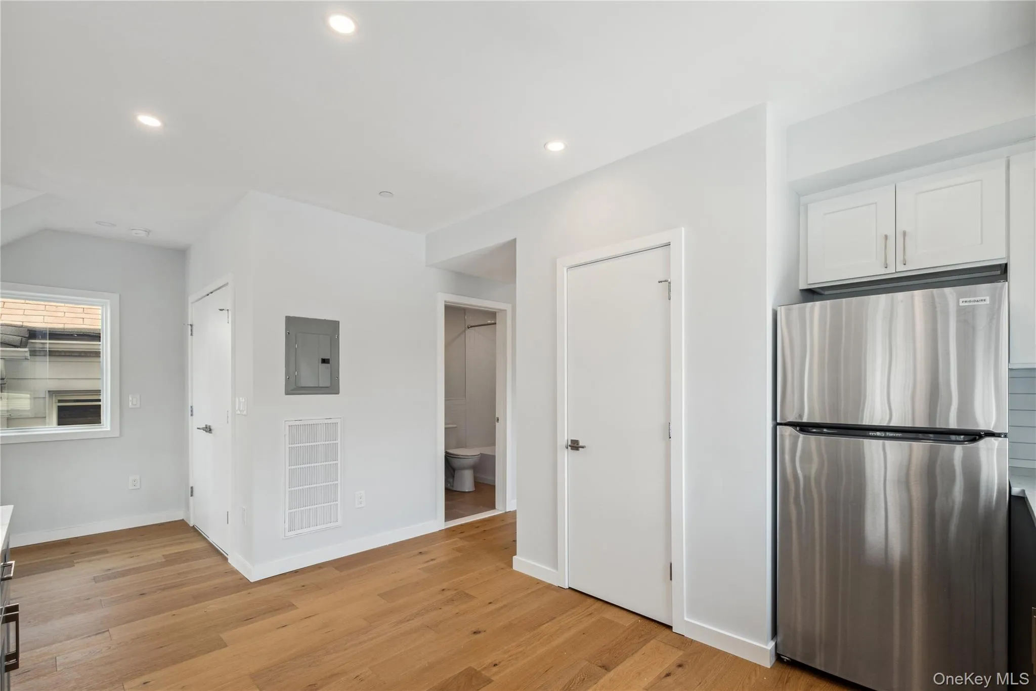 Kitchen featuring freestanding refrigerator, electric panel, light wood-style flooring, white cabinets, and recessed lighting Kitchen featuring freestanding refrigerator, electric panel, light wood-style flooring, white cabinets, and recessed lighting