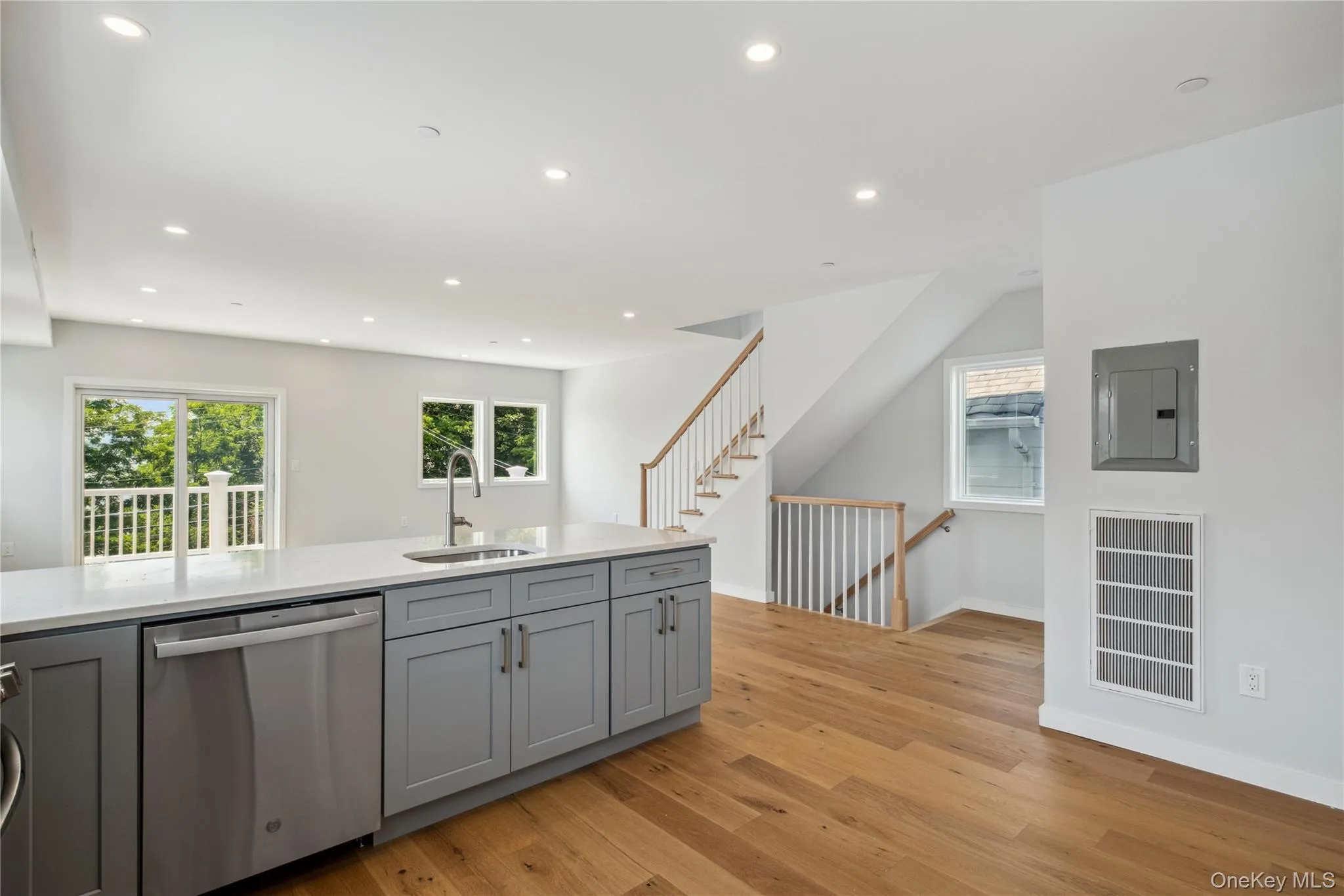 Kitchen with dishwasher, electric panel, gray cabinets, light wood-style flooring, and recessed lighting Kitchen with dishwasher, electric panel, gray cabinets, light wood-style flooring, and recessed lighting