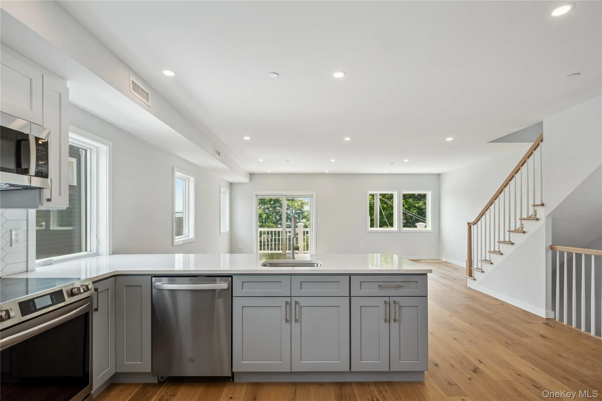 Kitchen with stainless steel appliances, gray cabinets, recessed lighting, light wood-type flooring, and a peninsula Kitchen with stainless steel appliances, gray cabinets, recessed lighting, light wood-type flooring, and a peninsula