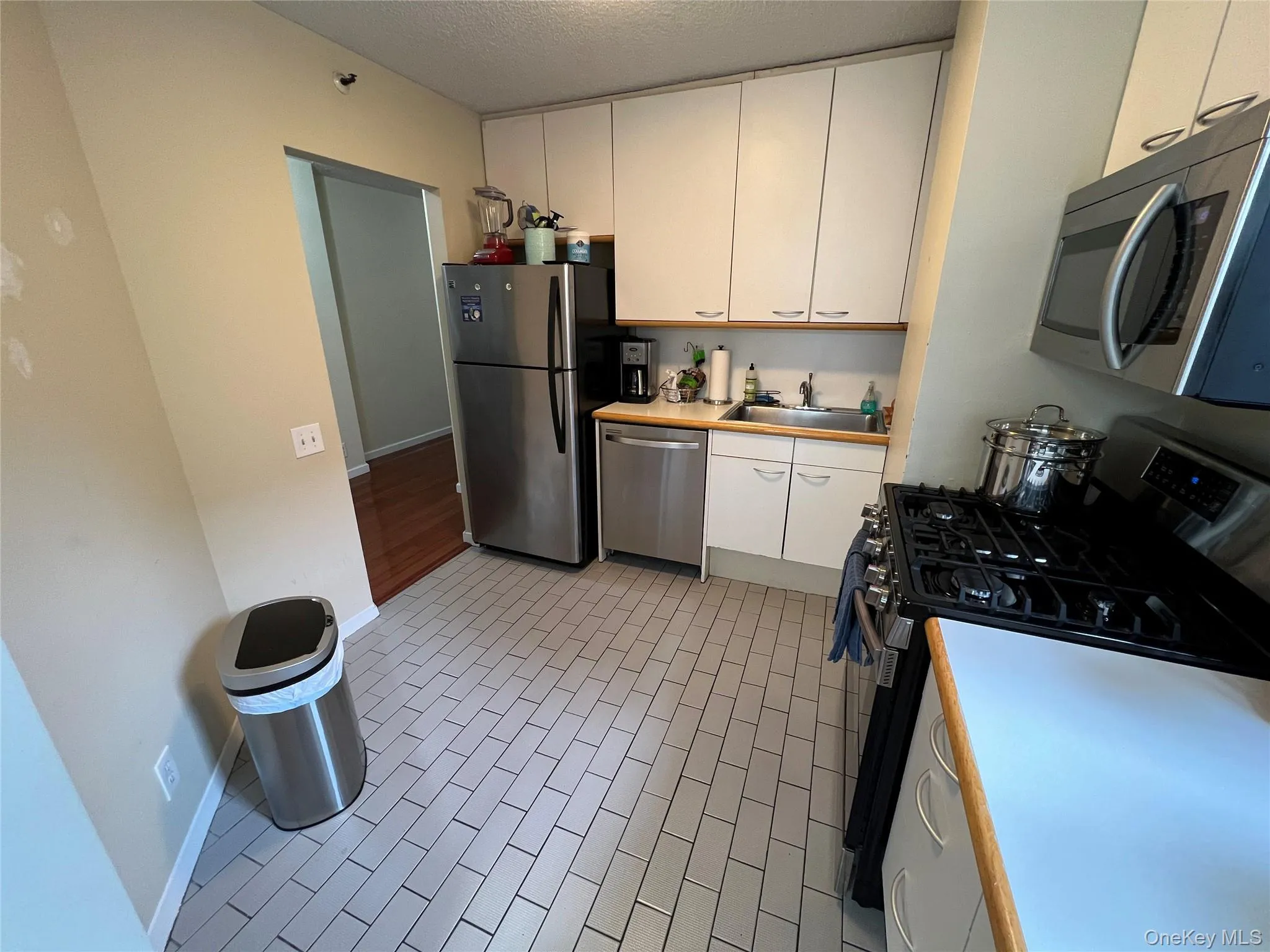 Kitchen featuring baseboards, a sink, light countertops, appliances with stainless steel finishes, and white cabinetry Kitchen featuring baseboards, a sink, light countertops, appliances with stainless steel finishes, and white cabinetry
