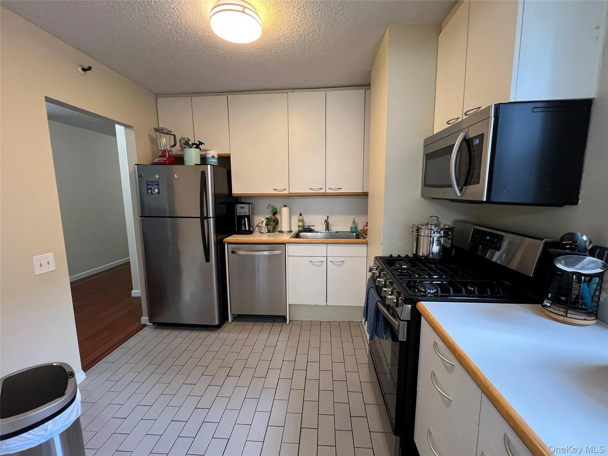 Kitchen with a textured ceiling, light countertops, white cabinets, appliances with stainless steel finishes, Kitchen with a textured ceiling, light countertops, white cabinets, appliances with stainless steel finishes,