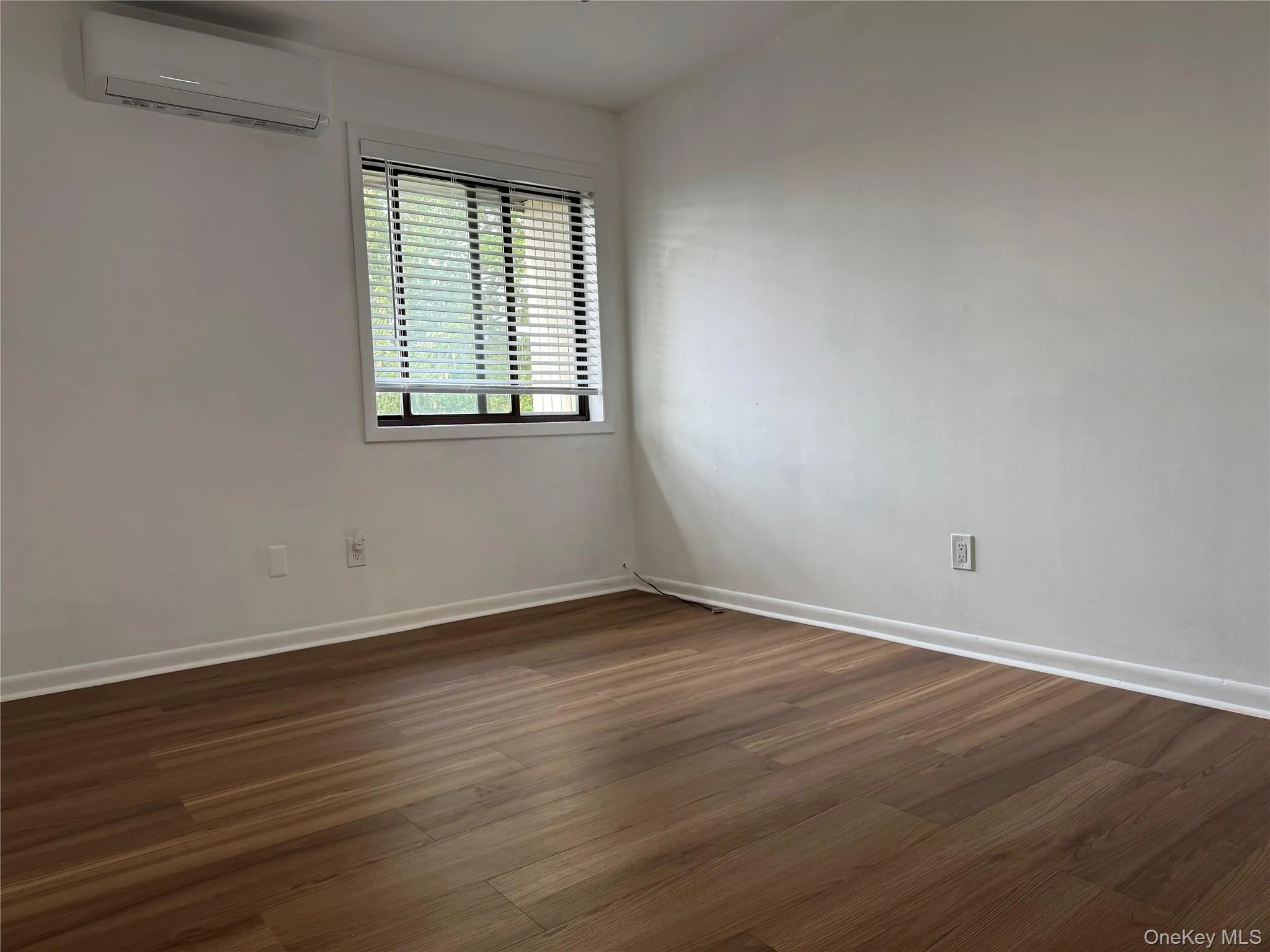 Unfurnished room featuring dark wood-style floors and an AC wall unit Unfurnished room featuring dark wood-style floors and an AC wall unit